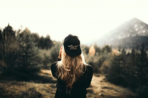 a girl near the trees looking at the mountain